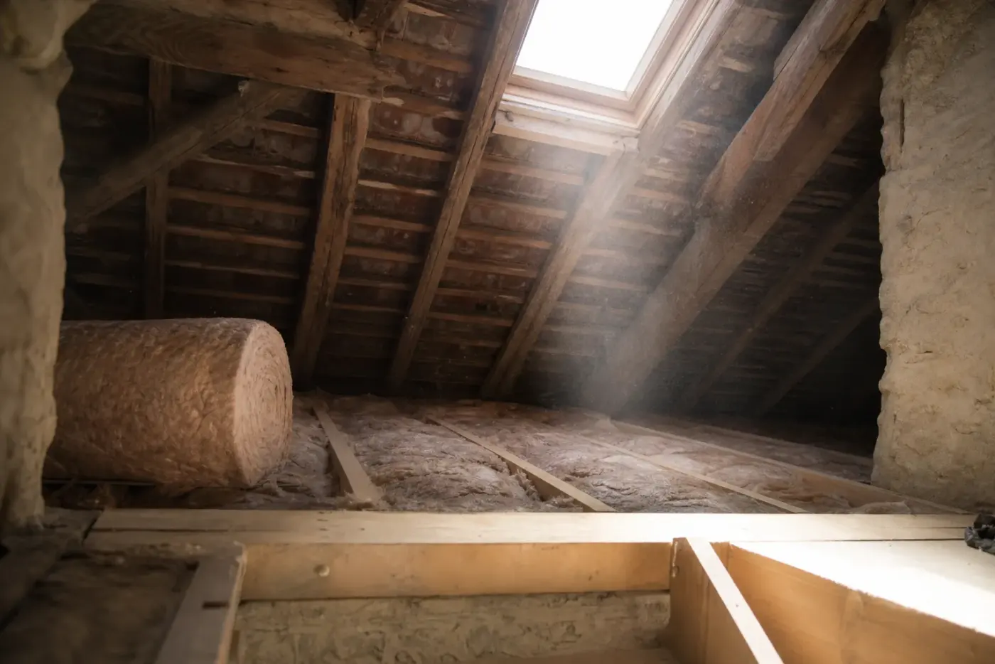 Pose d'un isolant en laine entre les solives des combles d'une maison