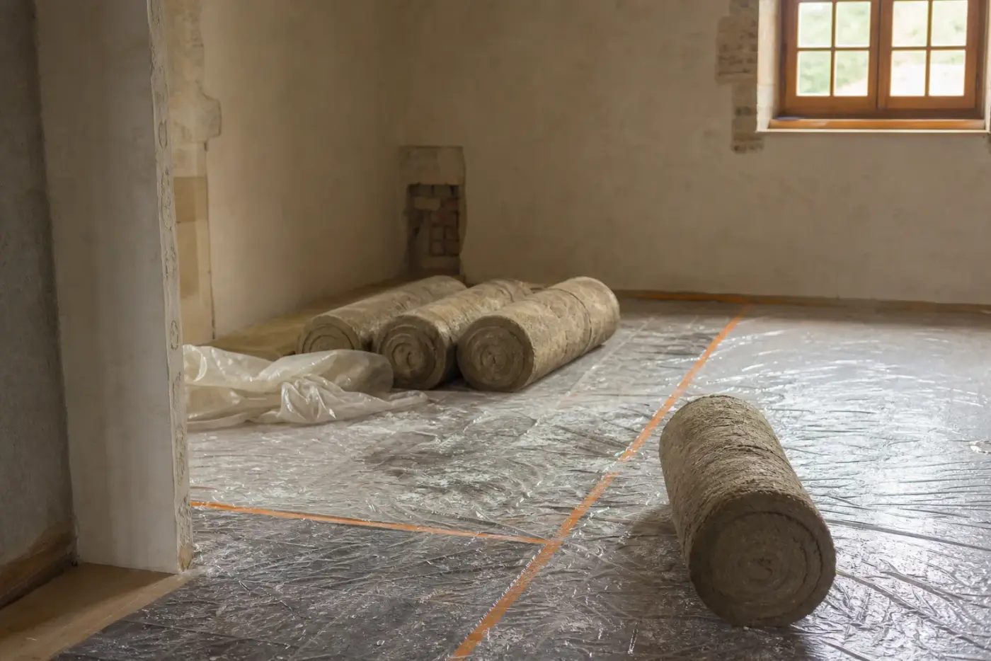 Rouleaux d'isolant posés au sol dans une pièce en cours de rénovation