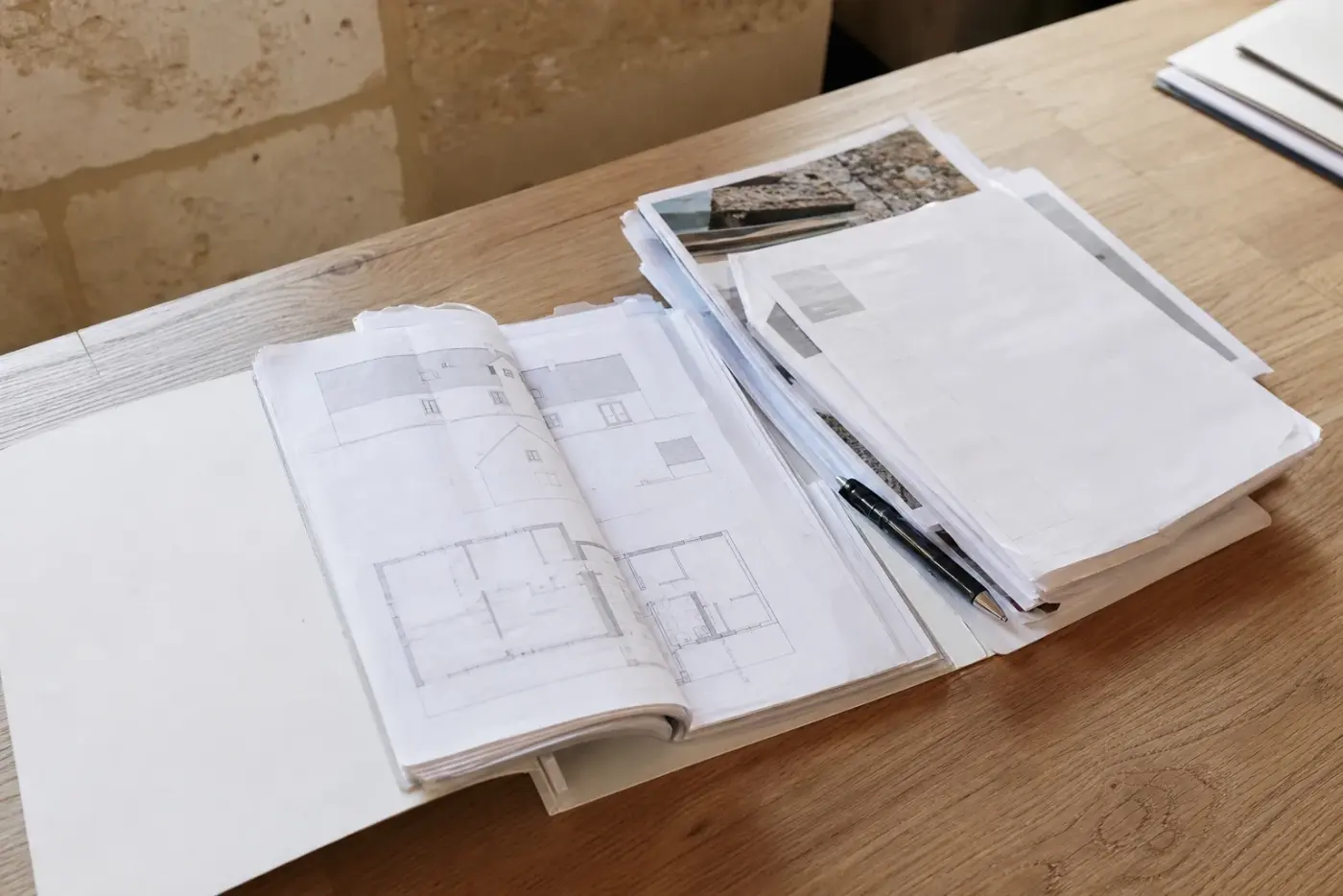 Dossier de travaux ouvert sur une table avec plans et documents