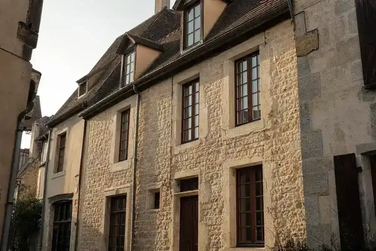 Façade en pierre d'un immeuble ancien de centre historique aux menuiseries bois
