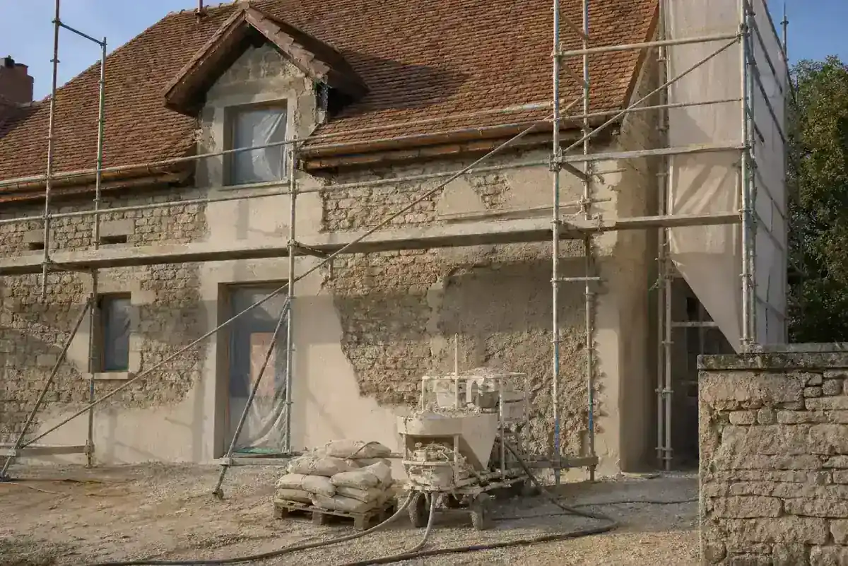 Maison sous échafaudage pendant la purge de l’enduit de façade