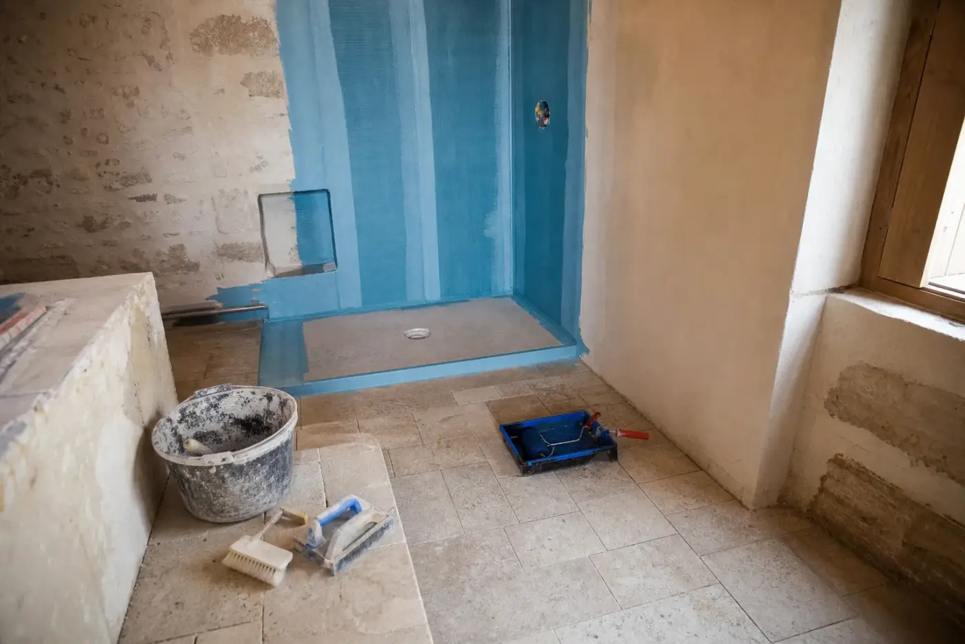 Application de l’étanchéité sous carrelage dans une douche en travaux